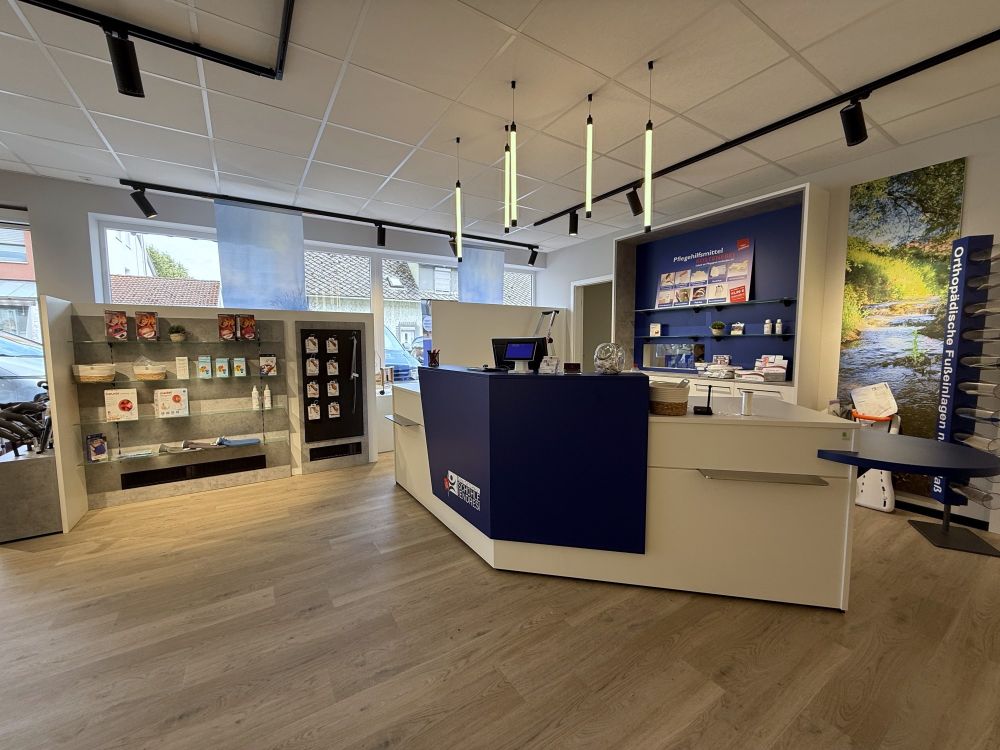 Funktional gestalteter Kassenbereich mit abgesenkter Kassenzone für Rollstuhlnutzer:innen. Im Hintergrund wurde eine Furniturenwand integriert.